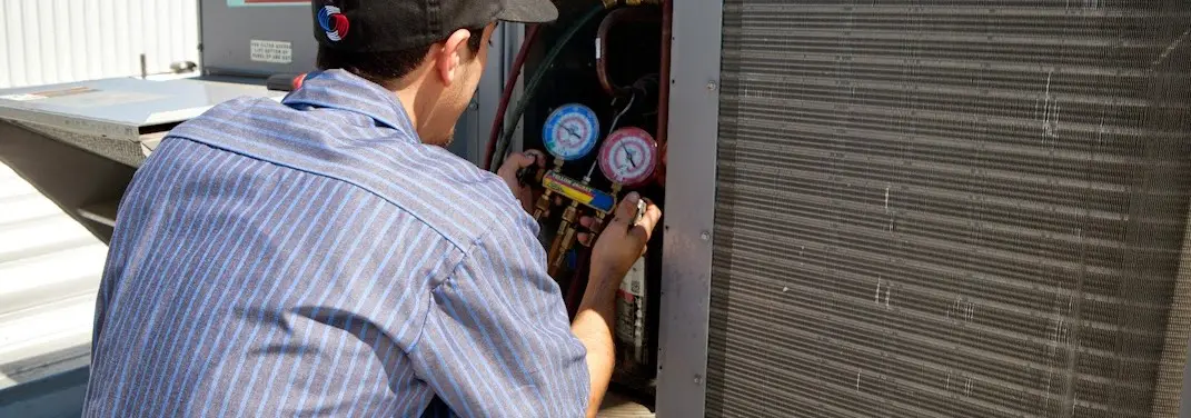 HVAC technician servicing a condenser unit in McPherson